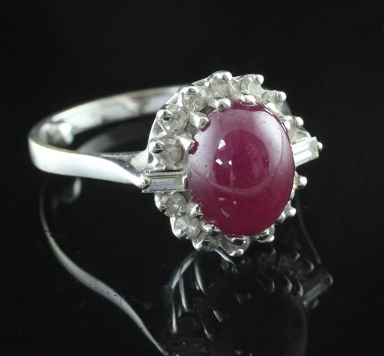 A white gold, cabochon ruby and diamond oval cluster ring, size M.